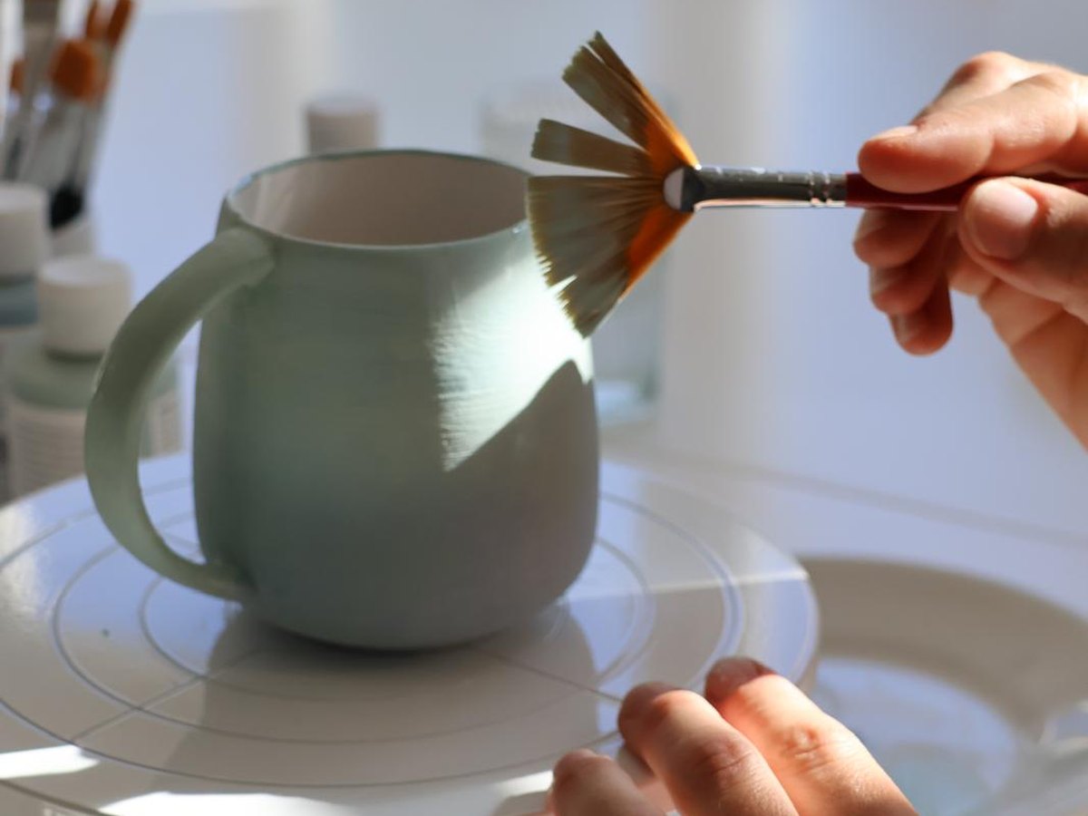 Hände bemalen eine Tasse im Atelier MARIE
